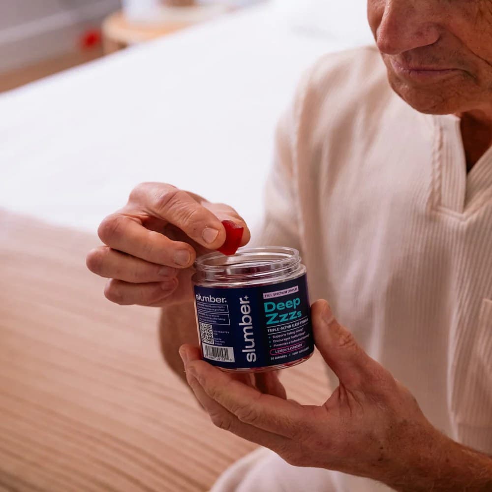 An older man holding a jar of Deep Zzzs sleep gummies